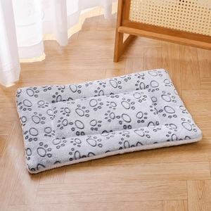 Grey plush pet blanket with dark claw prints on a wooden floor in a cozy home setting