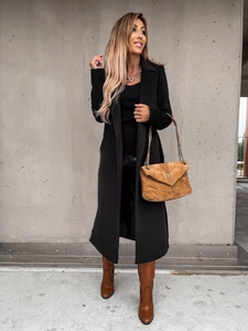 Detail of a black long wool coat with wide lapels and stylish brown suede bag