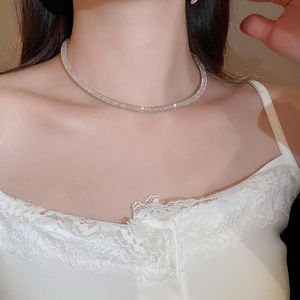 Macro shot of a silver twisted mesh necklace with zircon stones on model's neck