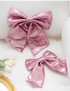 Detail of pink sequin bows for Christmas tree decoration on a white plush background