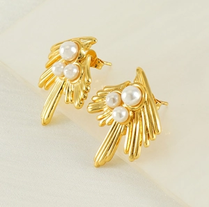 Detailed view of 18K gold swallow stud earrings with pearls on a matte surface