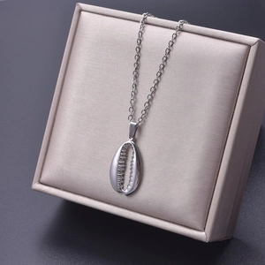 Detailed shot of a silver shell pendant necklace displayed in a beige silk jewelry box
