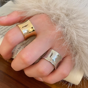 Close-up of polished gold and silver wide-band rings worn on hand for fashion