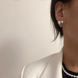 Close-up of heart-shaped silver stud earring on ear to show actual size and minimal design