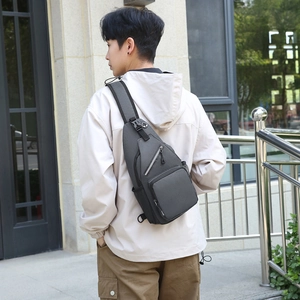 Men's grey nylon crossbody chest bag with multi-pocket layout shown on outdoor model