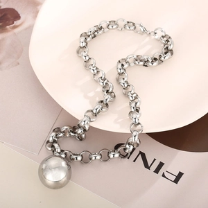 Détail macro d'un collier chaîne épaisse en acier inoxydable argenté avec pendentif boule polie