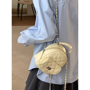 Detail of light yellow quilted mini bag with chain strap on a model in a cafe setting