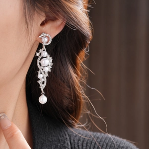 Close-up of elegant silver tassel earrings with white pearls and sparkling rhinestones