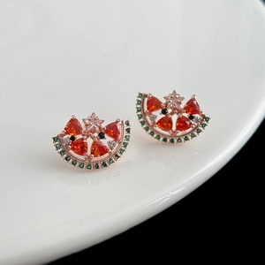 Macro de boucles d'oreilles pastèque avec pierres orange et vertes sur une assiette blanche