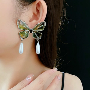 Detail of green butterfly tassel earrings with silver trim and elegant white pearl drop