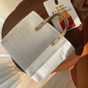 Detail of herringbone weave texture and beige leather straps on canvas tote bag