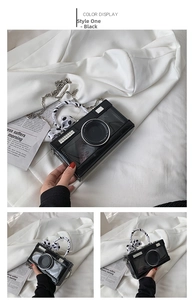 Creative black camera-shaped handbag featuring diamond accents and ribbon wrapped handle