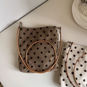 Detailed view of polka dot corduroy crossbody bags with simple wish side labels
