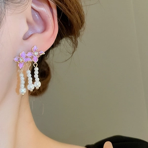 Detailed close-up of lavender enamel flower earrings with pearls on model side view