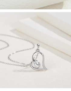 Detailed view of silver heart pendant with mother and child silhouette and zircon inlay