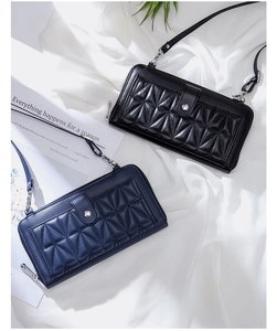 Detail of black and navy quilted leather crossbody bags on white fabric background
