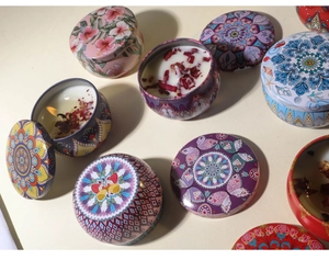 Close-up of scented soy wax candles with dried flowers in decorative metal tins