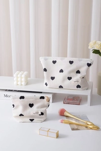 Detail view of heart pattern cosmetic bags in two sizes on a white decorative display