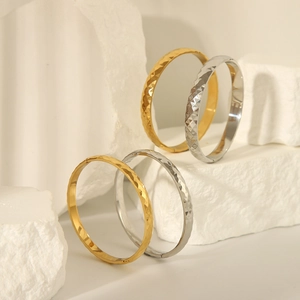 Detailed view of 18k gold and silver stainless steel bangles with rhombic pattern texture