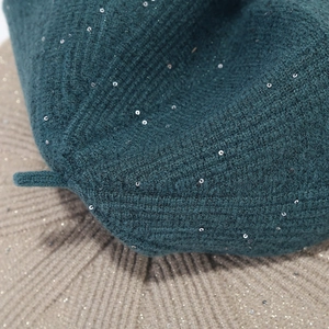 Detail of dark green knit beret with silver sequins and rib texture close-up