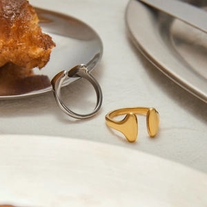 Minimalist stainless steel open rings in gold and silver on a textured light fabric