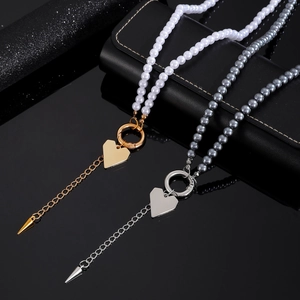Collana di perle con ciondolo a cuore e chiusura a cerchio su superficie nera riflettente