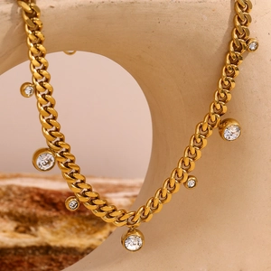 Close-up of golden cuban link necklace featuring multiple sparkling zircon charms