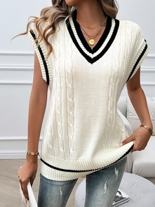 Detail of cable knit pattern and black striped trim on white V-neck sweater vest