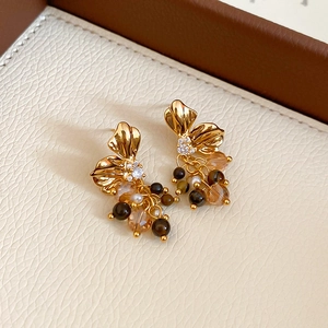 Macro detail of golden flower tassel earrings with zircon and tiger eye beads