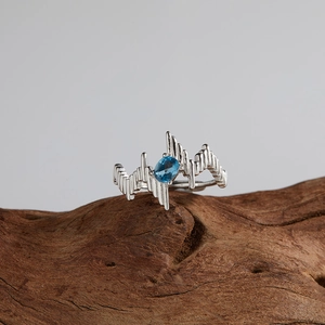 Macro detail of silver S925 ring with oval blue topaz on natural wooden block