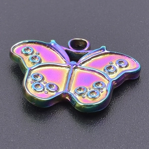 Macro detail of rainbow iridescent butterfly pendant on a textured black surface