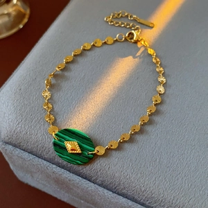 Détail d'un bracelet vintage en chaîne dorée avec pierre malachite verte et fermoir mousqueton
