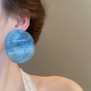 Detail of oversized blue translucent resin geometric earring with ice-crack texture