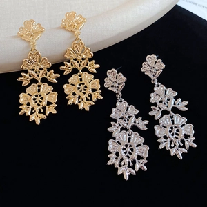 Detail of hollow floral tassel earrings in gold and silver finish with brushed texture