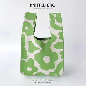 Close-up of a knitted floral tote bag with a soft green and cream poppy pattern texture