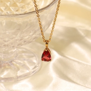 Macro shot of a red pear-shaped zircon pendant on an 18K gold-plated stainless steel chain