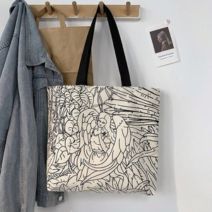 Detail of canvas tote bag with artistic line drawing print on a wooden wall hook