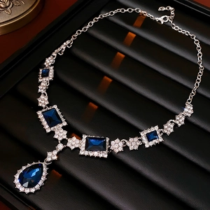 Macro view of blue teardrop pendant necklace with sparkling rhinestone borders on black display