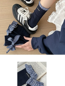 Detail of dark blue ribbed crew socks with plaid bow and lace trim decoration