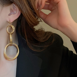 Detail of gold triple-linked hoops on model showing metallic brushed texture and style