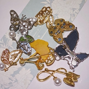 Détail de broches papillon avec métal or et argent, feuilles en émail et détails en perles