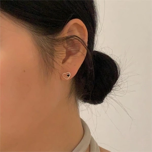 Close-up of heart-shaped silver earrings with black drip oil on a female model