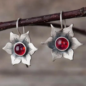 Gros plan de boucles d'oreilles vintage en argent avec pierre rouge sur branche