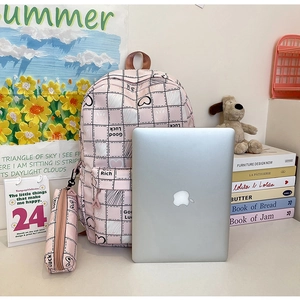 Pink checkered nylon school bag set with rabbit print on white desk with laptop