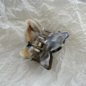 Macro shot of 3D marble texture butterfly hair claw with golden metal spring