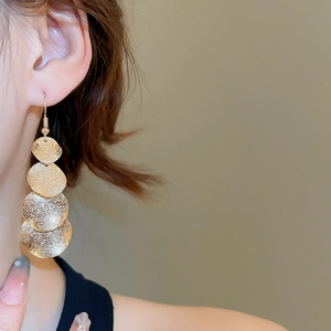 Close-up of matte gold multi-layer disc tassel earrings on model for size and style