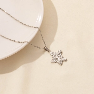 Detail of silver starfish pendant with hammered texture on a white ceramic plate