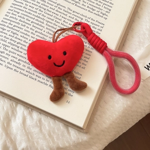 Macro shot of red heart plush keychain with braided handle strap on a vintage book