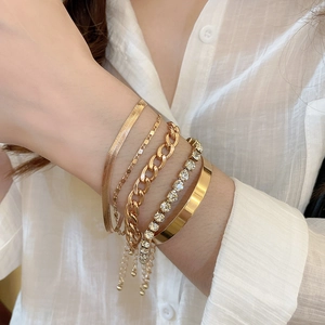 Gros plan de bracelets chaîne en or superposés et d'un jonc sur un mannequin