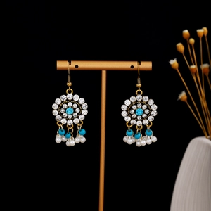 Detail of ethnic bohemian gold earrings with blue gemstones and white pearl tassels